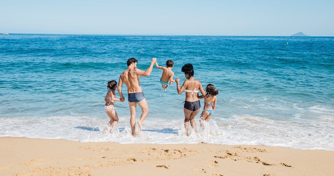 Famiglia che corre felice tra le onde del mare in Calabria